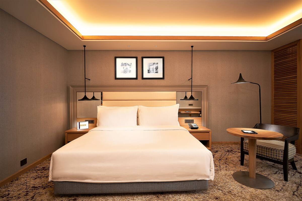 Une chambre d’hôtel avec un grand lit, des tables de chevet, une table ronde et une chaise.