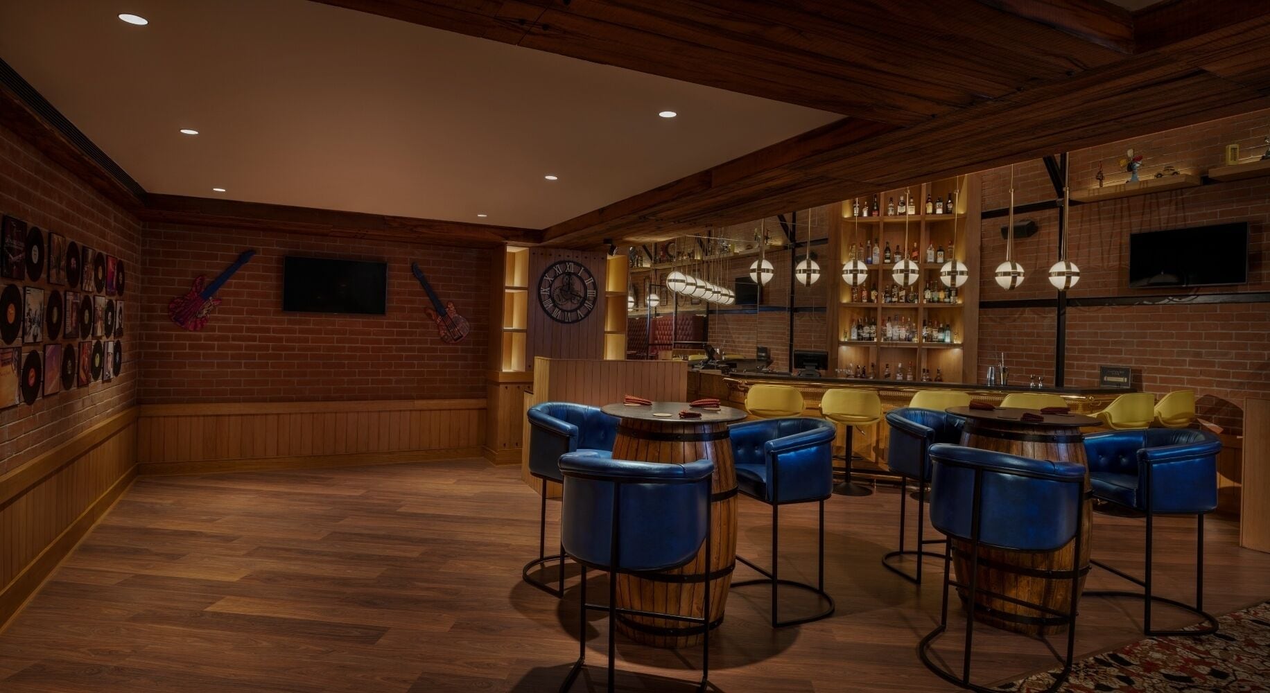 Un espace bar avec des murs en bois, une cheminée en briques et des tabourets de bar bleus.