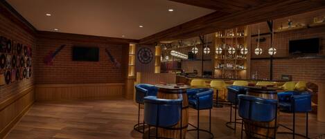 Un espace bar avec des murs en bois, une cheminée en briques et des tabourets de bar bleus.