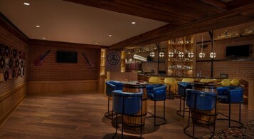 Un área de bar con paredes de madera, una chimenea de ladrillo y taburetes azules.