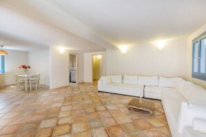 A spacious living room with a white sofa, a coffee table, and a dining area with a table and chairs.