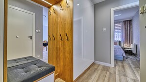 Een moderne slaapkamer met een grijs bed, een houten kledingkast en een zithoekje.