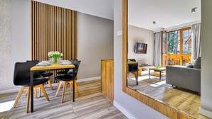 Een moderne eethoek met een houten tafel, zwarte stoelen en een vaas witte bloemen.