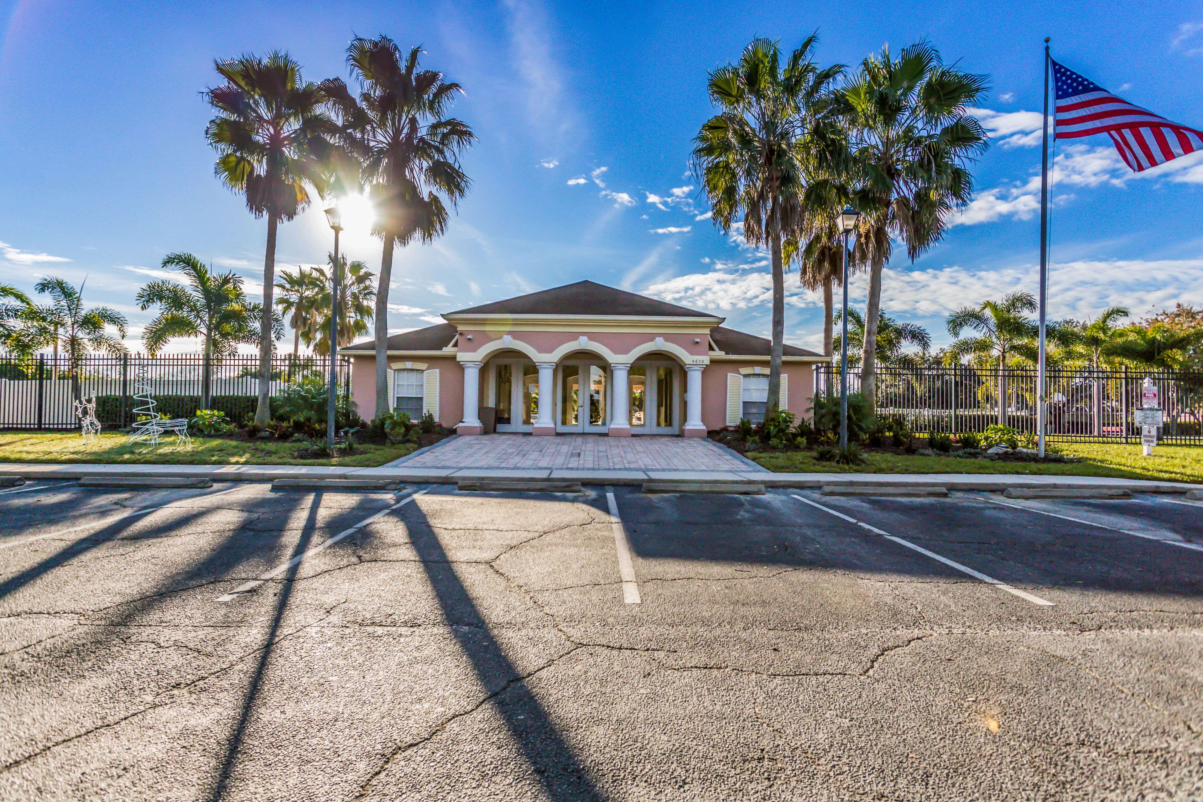 A building with a symmetrical facade, palm trees, and an American flag.