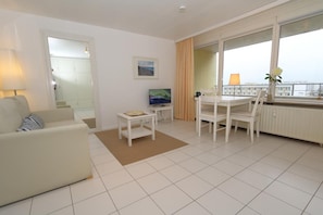 Un salon moderne comprenant un canapé, une petite table, un téléviseur et un coin repas avec des chaises.