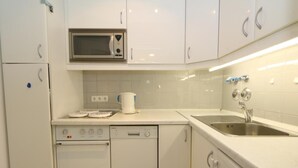 A compact kitchen with white cabinets, a microwave, a dishwasher, and a sink. - Metropol House, apt. 109 (Sylt)