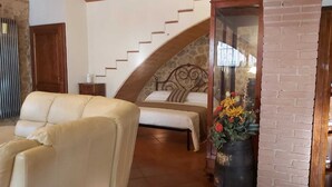 Ein Schlafzimmer mit Steintreppe, einem Bett, einer Couch und einer Vase mit Blumen.