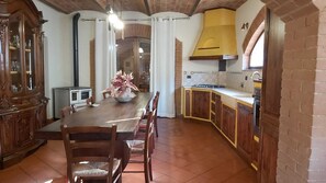 A kitchen with a wooden table, chairs, a stove, and cabinets.