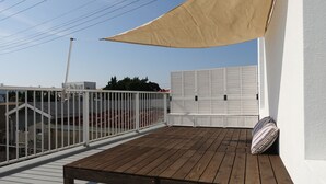 A wooden deck with a bench and a canopy, overlooking a white fence and buildings. - Hostel NABLA (Niijima)