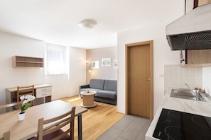 A compact living space with a dining area, a sofa, a small coffee table, and a kitchenette. - Apartments Medved (Koper)