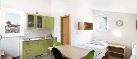 A compact room with a kitchenette, a dining area, and a bed.