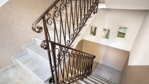 Una scala con ringhiera in ferro battuto e un muro con tre quadri incorniciati.