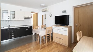 Una cucina moderna con mobili neri e bianchi, un tavolo da pranzo con sedie, una televisione a schermo piatto e una porta in legno.