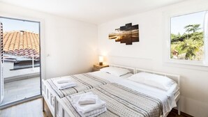 Una camera da letto con un letto, un comodino, un'opera d'arte appesa al muro e una finestra vista su piante.