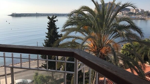 A balcony with a view of a calm sea, palm trees, and a distant cityscape. - Beachfront house. WIFI. Smart TV (Águilas)