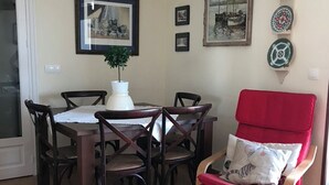 A dining area with a round table, six chairs, a potted plant, and a red armchair with a cushion. - Beachfront house. WIFI. Smart TV (Águilas)