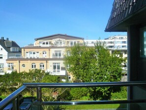 Un immeuble d’habitation doté d’un balcon, entouré de verdure et d’autres bâtiments.