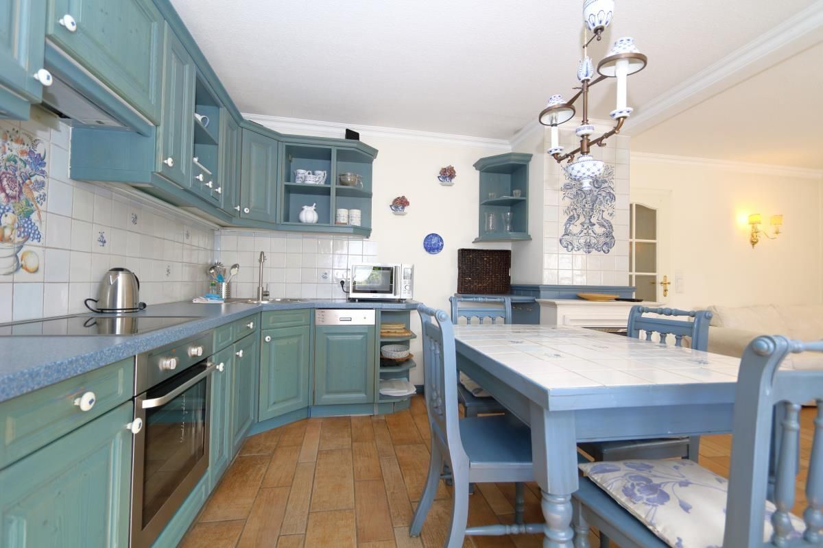 A kitchen with teal cabinets, a microwave, and a dining table with chairs.