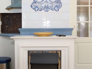 Une cheminée avec un manteau de couleur blanche et un pare-feu en carreaux bleus.