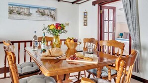 Een eetgedeelte met een houten tafel, gedekt voor een maaltijd, met brood, kaas en een schaal fruit.