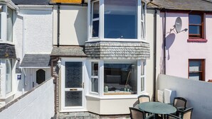 Een hoekwoning met erker, een schotelantenne en een klein terras met een tafel en stoelen.