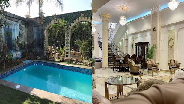 Een zwembad met een waterval en een luxueus interieur, met sierlijk meubilair en een statige trap.