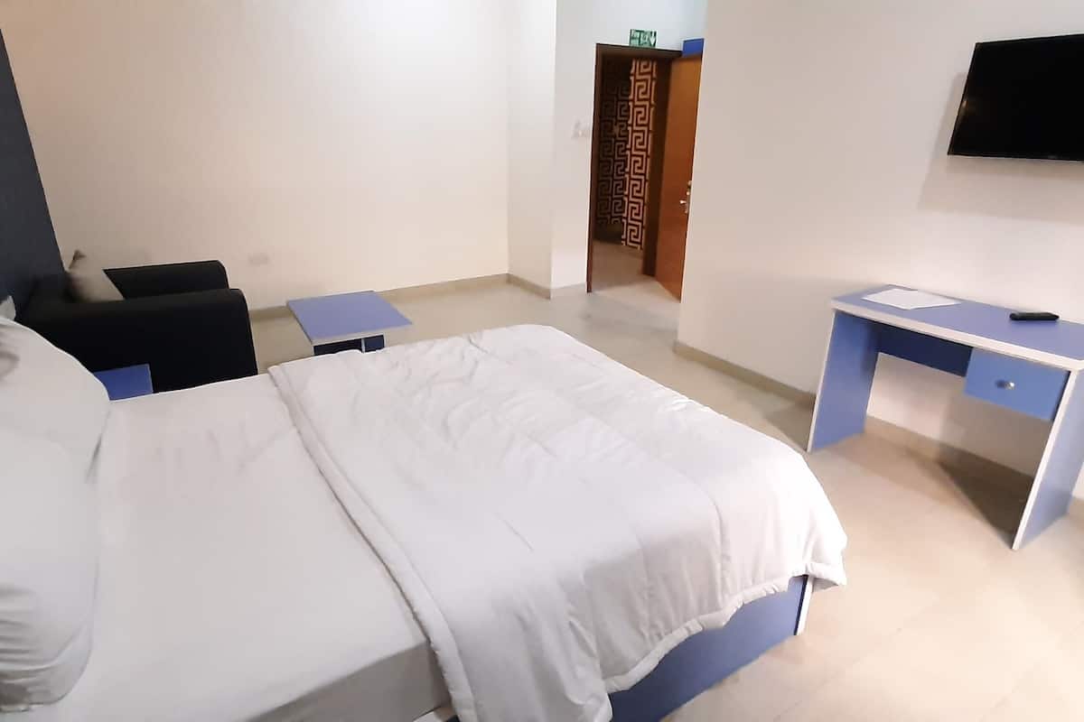 A hotel room with a bed, a desk, a chair, and a television.
