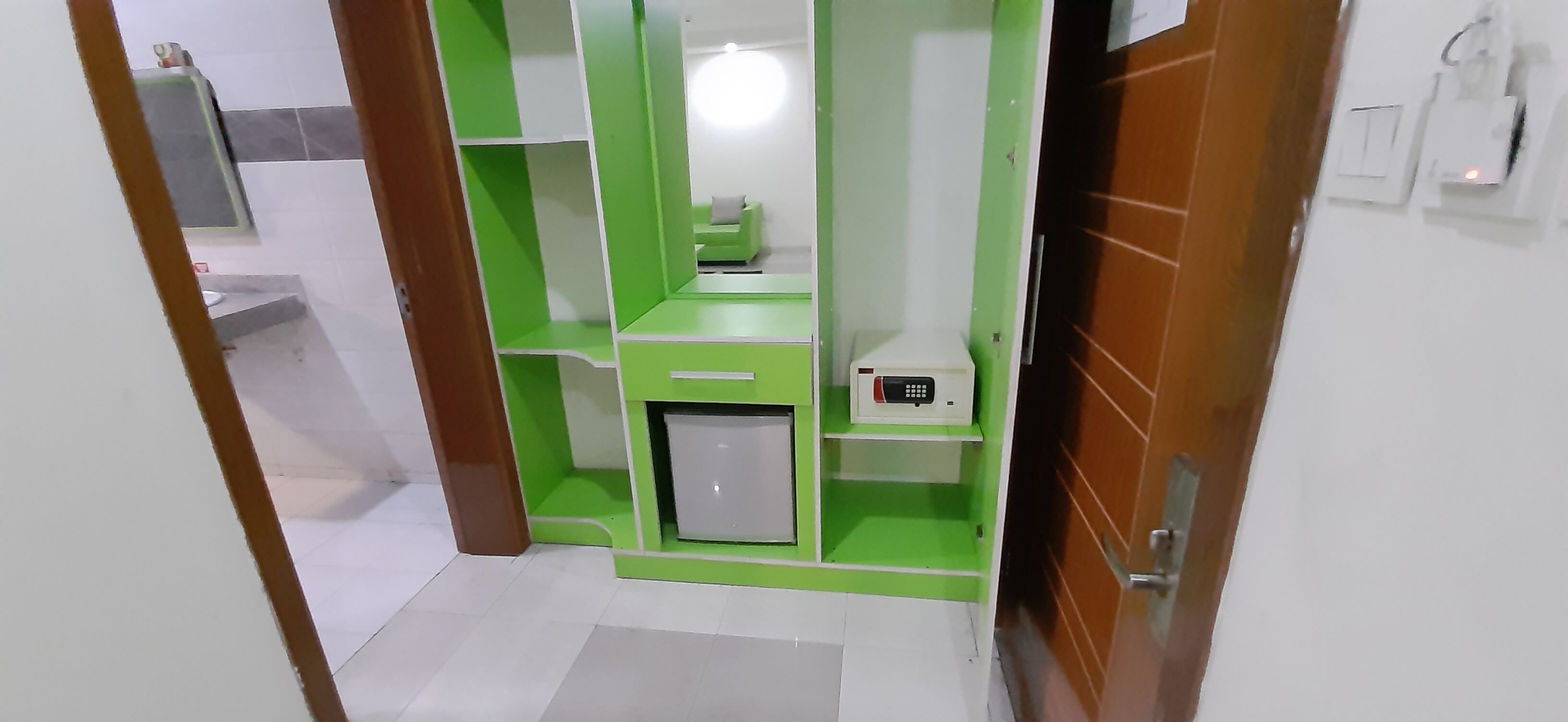 A small, compact bathroom with a green vanity, a toilet, and a shower area.