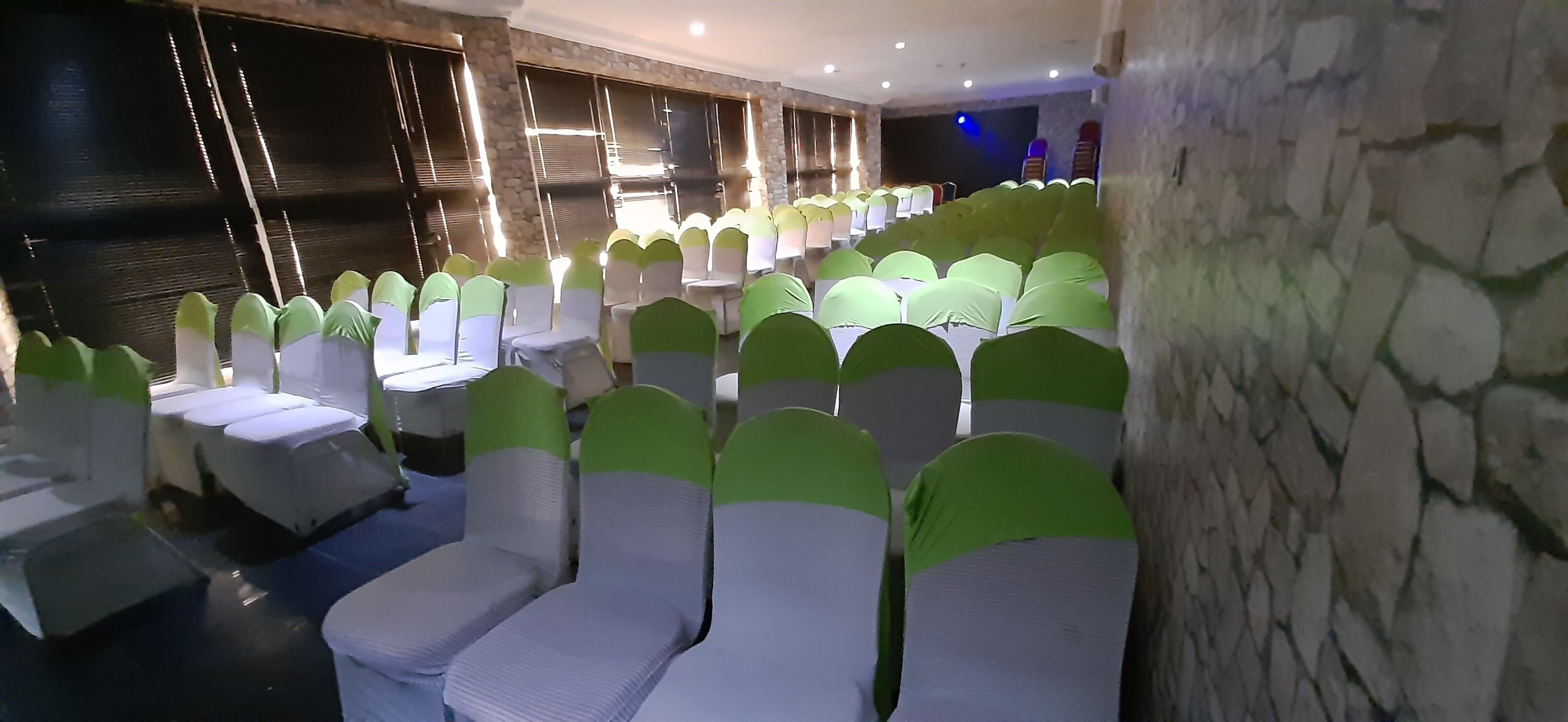 A banquet hall with rows of tables and chairs, stone walls, and a stage with lighting.