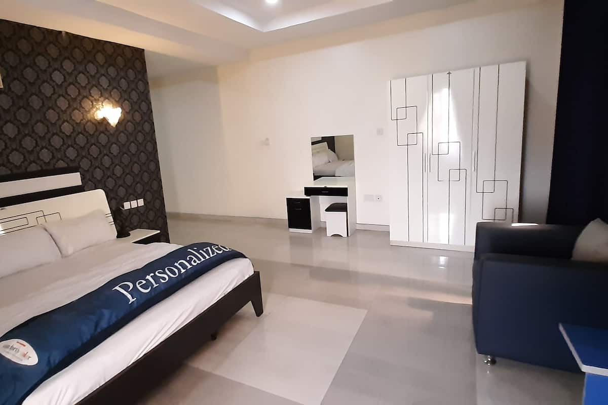 A modern bedroom with a large bed, a desk, and a wardrobe.