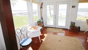 A room with a view of a lake, a dining table with chairs, a large rug, and a wooden floor. - Beautiful lakefront cottage on Chautauqua Lake in a quiet setting! (Jamestown)