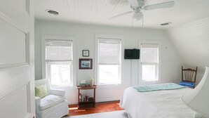 A bedroom with a bed, a chair, a small table, and a ceiling fan. - Beautiful lakefront cottage on Chautauqua Lake in a quiet setting! (Jamestown)