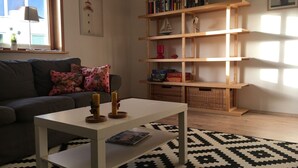 A living room with a sofa, a coffee table, a bookshelf, and a patterned rug.