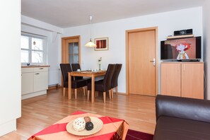 Un espace de vie compact comprenant un coin repas, une kitchenette et un téléviseur.