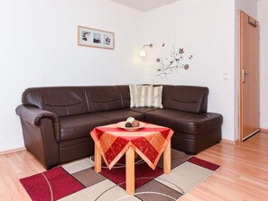 Un canapé en cuir marron, avec une petite table placée devant, une nappe à motifs rouges et blancs, et un élément décoratif mural.
