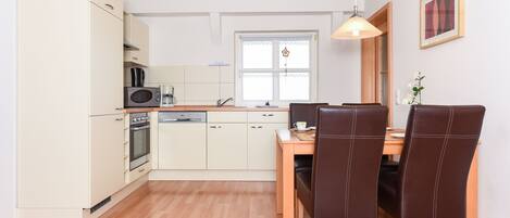 Cocina compacta con comedor, que incluye microondas, horno y pileta.