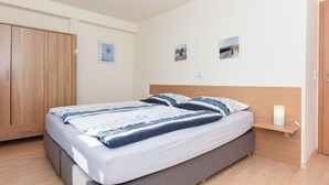 Et soveværelse med seng, træskab og et natbord med lampe.