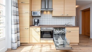 Une cuisine moderne avec des meubles en bois, un four encastré, un four à micro-ondes et un lave-vaisselle.