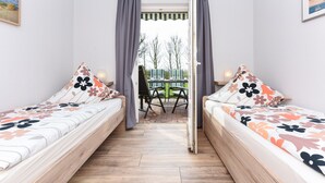 Une chambre avec deux lits, une table avec des chaises et une vue sur l’extérieur.