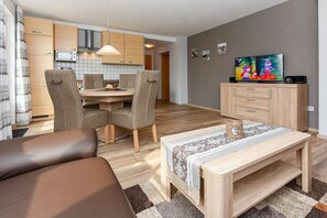 Un salon moderne avec un canapé, une table basse en bois et un téléviseur posé sur un meuble.