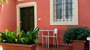 A building with a green door, a window with a grid pattern, and a white chair outside.