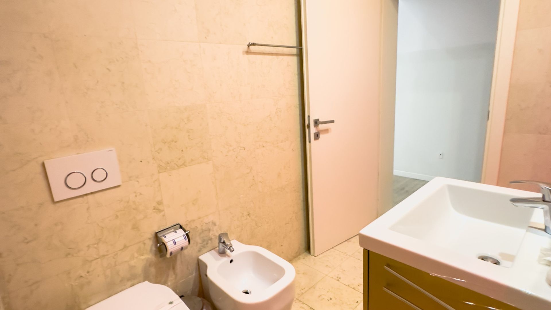 Ein Badezimmer mit Waschbecken, Bidet, Toilette und Handtuchspender.