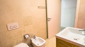 A bathroom with a white sink, a bidet, a toilet, and a towel dispenser. - Juliet House (Verona)