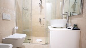 Un baño moderno con ducha envuelta en vidrio, un lavamanos blanco de gran tamaño y un inodoro.