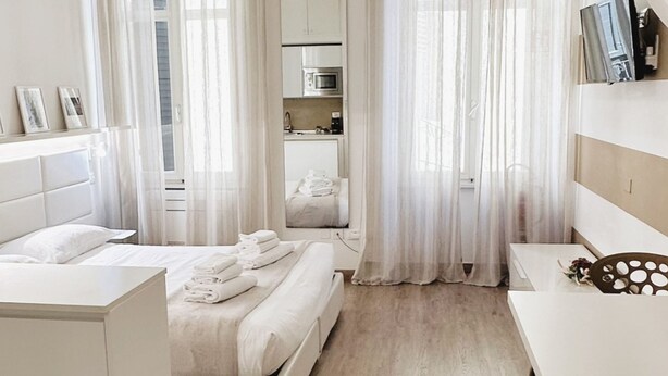 Habitación de hotel con cama, escritorio, silla, kitchenette y baño.