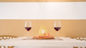 Una mesa con mantel blanco, dos copas de vino y un plato de comida.
