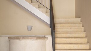 Una escalera con barandilla, una lámpara y una luz empotrada en la pared.