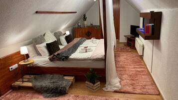 A bedroom with a bed, bedside table, lamp, bedside plant, and a wooden headboard.