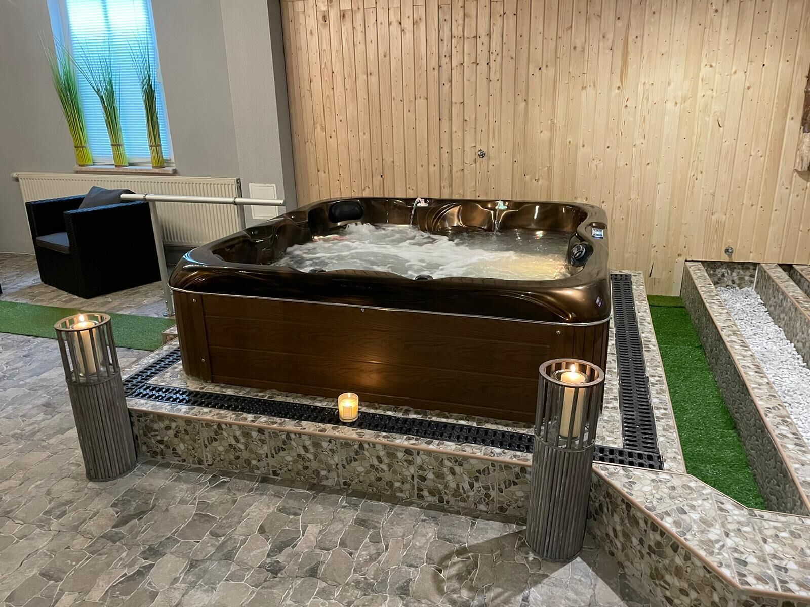 Een whirlpool in een wellnessruimte, met een houten wand en stenen vloer.