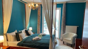 A bedroom with a four-poster bed, a chandelier, and a view of the outdoors.
